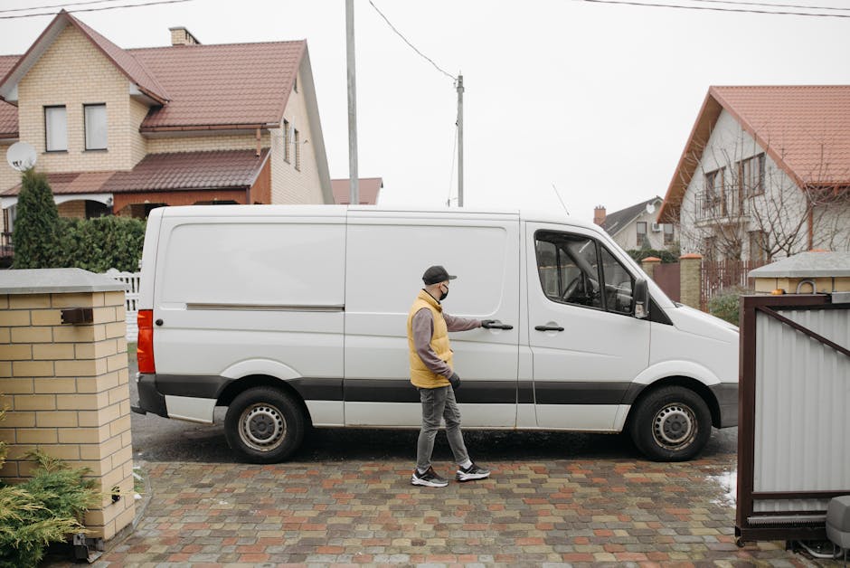 A man wearing a white t-shirt, jeans, white sneakers, and a black cap is engaged in a home relocation task as part of a professional removal service by Man and Van Abbey Wood. He is carrying a medium-
