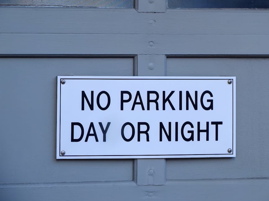 A circular no parking sign with a red border and a black letter 'P' crossed out by a red diagonal line, mounted on a metal pole against a cloudy grey sky. This sign indicates parking restrictions in the area, which could impact house removals and furniture transport logistics during a home relocation. Temporary parking limitations like this are relevant for professional removals services, such as those provided by Man and Van Abbey Wood, especially when planning moving activities on narrow streets or areas with specific parking rules. Proper planning for loading and unloading areas is essential to ensure smooth packing and moving processes, including loading furniture, boxes, and appliances into vans or trucks. The image highlights the importance of adhering to parking regulations to facilitate efficient house removals, particularly in urban or congested settings like Abbey Wood, especially when coordinating with removal professionals for a detailed SE2 flat removals guide.